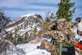 Hunter wearing camo uses binoculars to scope out a deer, as a llama watches