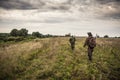 Hunters going through rural field with dramatic sky during hunting season