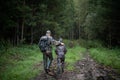 Hunters with hunting equipment going away through rural field towards forest at sunset during hunting season in