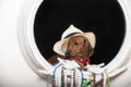A dog of the red dachshund breed, sitting in a white straw hat, is reflected in an antique mirror with an ivory frame.