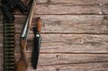 The border is made of hunting weapons, bandolier with cartridges, binoculars and a knife in a case on a wooden background.