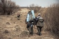 Hunting scene with hunters with backpacks and hunting ammunition going across rural area with bushes during hunting season Royalty Free Stock Photo