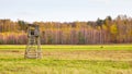 Hunting tower in a field with autumnal forest in background Royalty Free Stock Photo