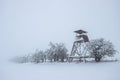 Hunting tower in winter landscape. Heavy snowing