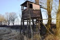 Hunting watchtower on a meadow, sunny winter afternoon.