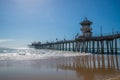 The Huntington Beach Pier as seen on a sunny day from a beach view looking up showing the concrete pillars on the underside of the