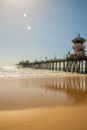 The Huntington Beach Pier as seen on a sunny day from a beach view looking up showing the concrete pillars on the underside of the