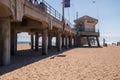 The Huntington Beach Pier as seen on a sunny day from a beach view looking up showing the concrete pillars on the underside of the