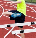 Hurdle runner performing sports drills on a red track