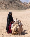 Camel and a Bedouin woman. Muslim woman wears a black hijab in Egypt. Local people of Africa