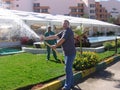 Hurghada, Egypt - October 27, 2019: people watering green lawns from hoses. Water splashes under high pressure. Men are laughing.