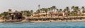 Beach with palms tree in Hurghada, tourists with sunbeds and umbrellas on the hot summer day Royalty Free Stock Photo