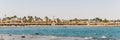 Beach with palms tree in Hurghada, tourists with sunbeds and umbrellas on the hot summer day Royalty Free Stock Photo