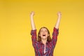 Hurray, victory! Portrait of delighted girl in checkered shirt yelling for happiness, enjoying life, rejoicing success with arms