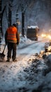 Hurricane aftermath: Road worker in protective gear shovels sidewalk, clearing snow-covered road.