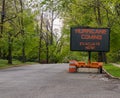 Hurricane Coming Evacuate Now warning information sign on trailer with LED face on street lined with trees Royalty Free Stock Photo