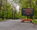 Hurricane Coming Seek Shelter warning information sign on trailer with LED face on street lined with trees