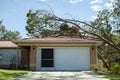 Hurricane damage to a house roof in Florida. Fallen down big tree after tropical storm winds. Consequences of natural Royalty Free Stock Photo