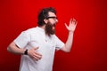 Hurried bearded man weating glasses is running over red background