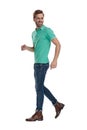 Hurried man in green polo shirt walking while looking back