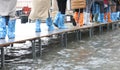 hurried people walk on the elevated walkway during high tide in