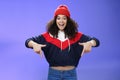 Hurry up and chek it out. Portrait of charismatic joyful and excited young cute curly-haired girl in beanie and stylish Royalty Free Stock Photo