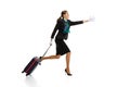 Full-length portrait of beautiful young woman, flight attendant running with suitcase isolated on white studio Royalty Free Stock Photo