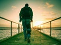 Hurt man with hooded jacket and forearm crutches standing on sea bridge Royalty Free Stock Photo