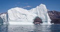 Hurtigruten`s MS Fridtjof Nansen expedition  cruise ship seen through an arch in a gigantic iceberg at Disko Bay, Greenland Royalty Free Stock Photo