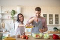 Husband adding spices to salad while cooking with wife Royalty Free Stock Photo