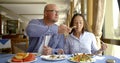 The husband bald and in glasses and the dark-haired middle-aged wife, sit in cafe, eat, laugh, communicate. A man pulls
