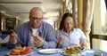 Husband bald and glasses and dark-haired middle-aged wife, sitting in a cafe, eat, communicate. Have them on the table