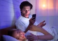 Husband Catching Wife Chatting On Phone In Bed At Night