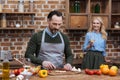 husband cutting vegetables and wife standing with glass