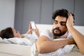 Husband is frustrated, upset while his internet addict wife is using mobile phone in social network Royalty Free Stock Photo