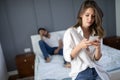 Husband is frustrated, upset while his internet addict wife is using mobile phone in social network Royalty Free Stock Photo