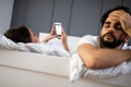 Husband is frustrated, upset while his internet addict wife is using mobile phone in social network Royalty Free Stock Photo