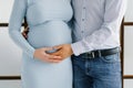 Future father holds his hand on the stomach of his pregnant wife, future mother in a blue light dress. She also keeps her hand on Royalty Free Stock Photo