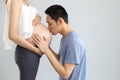 Husband giving kiss to young asian pregnant belly wife with love on white background Royalty Free Stock Photo