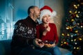 A husband and his wife enjoy popcorn on Christmas eve while watching TV and laughing loudly while watching movies Royalty Free Stock Photo