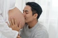 Husband kissing the belly wife near the window in the home. Handsome young man kissing the belly of his lovely pregnant Royalty Free Stock Photo