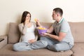 Husband offers chips to his pregnant wife but she refuses and makes stop gesture because she feels sick. Feeling bad during