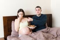 Husband offers cookies to his pregnant wife but she refuses and makes stop gesture because she feels sick. Feeling bad during