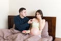 Husband offers donuts to his pregnant wife but she refuses and makes stop gesture because she feels sick. Feeling bad during