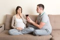 Husband offers a glass of red wine to his pregnant wife but she refuses and makes stop gesture because she feels sick. Feeling bad