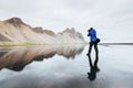 The husband is a photographer standing on the water surface at the coast of Iceland in Stokksnes