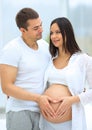 Husband and pregnant wife with folded hands in the shape of a heart on his tummy Royalty Free Stock Photo