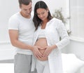 Husband and pregnant wife with folded hands in the shape of a heart on his tummy Royalty Free Stock Photo