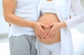 Husband and pregnant wife with folded hands in the shape of a heart on his tummy Royalty Free Stock Photo