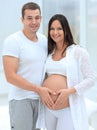 Husband and pregnant wife with folded hands in the shape of a heart on his tummy Royalty Free Stock Photo